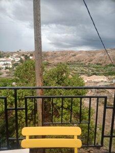 Yellow chair in the foreground is striking against black railings and a stormy view behind